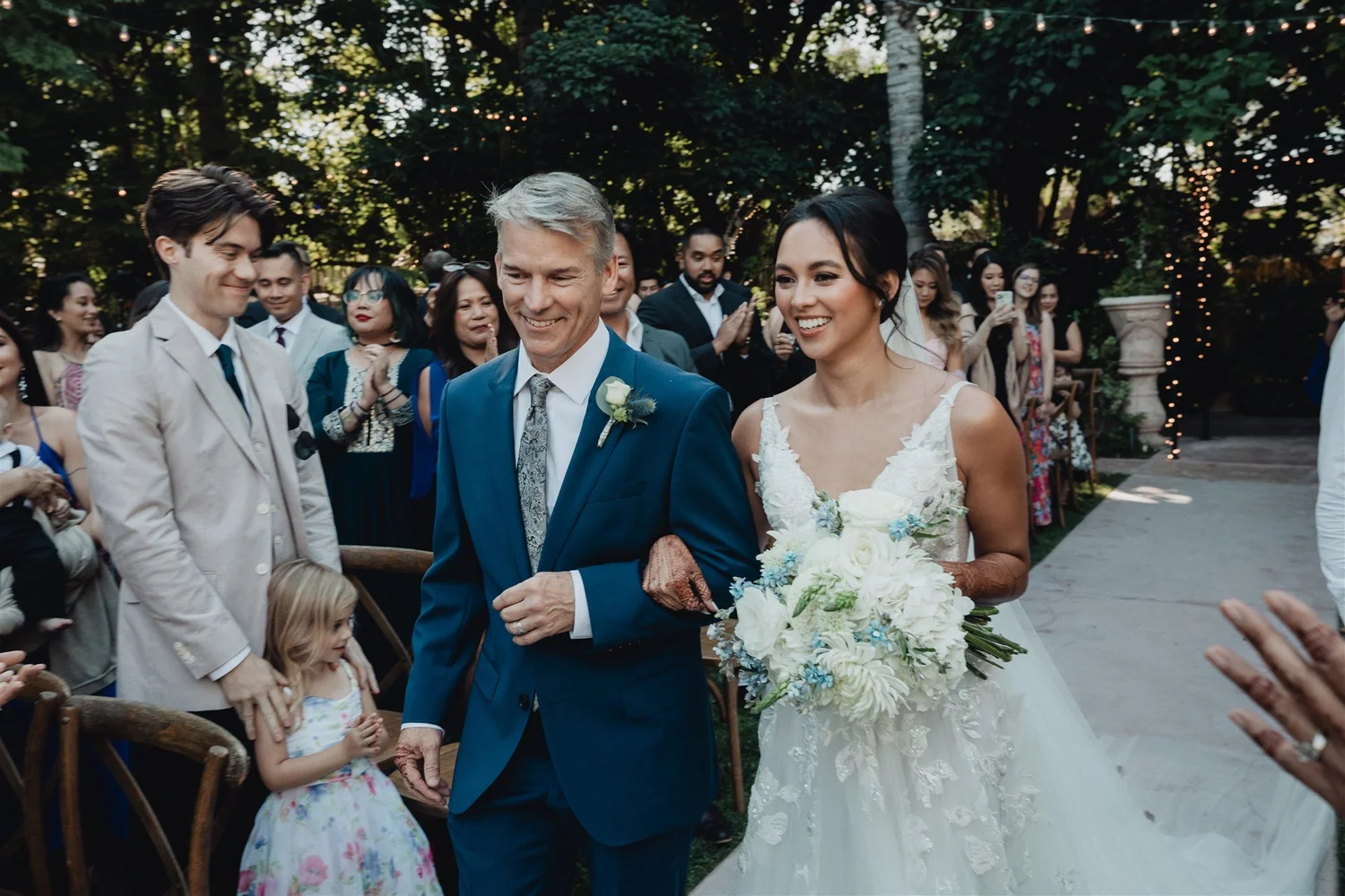 Bride walking down the aisle on her father’s arm past smiling guests