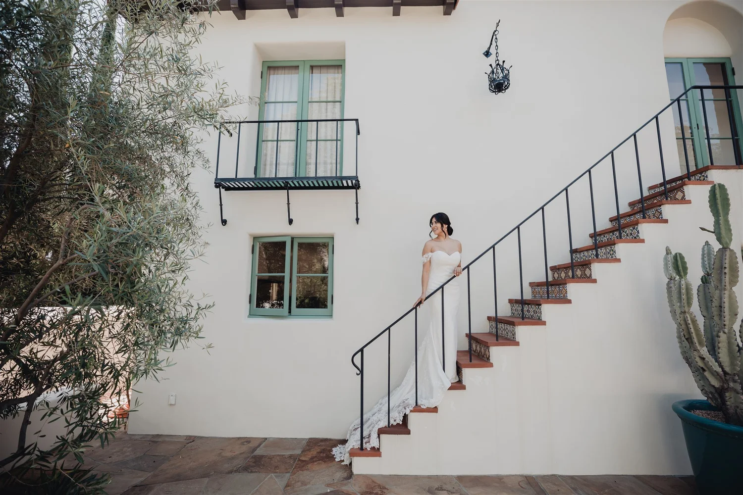 Bride on the exterior staircase of a white Spanish Colonial building near Grapevine Arbor