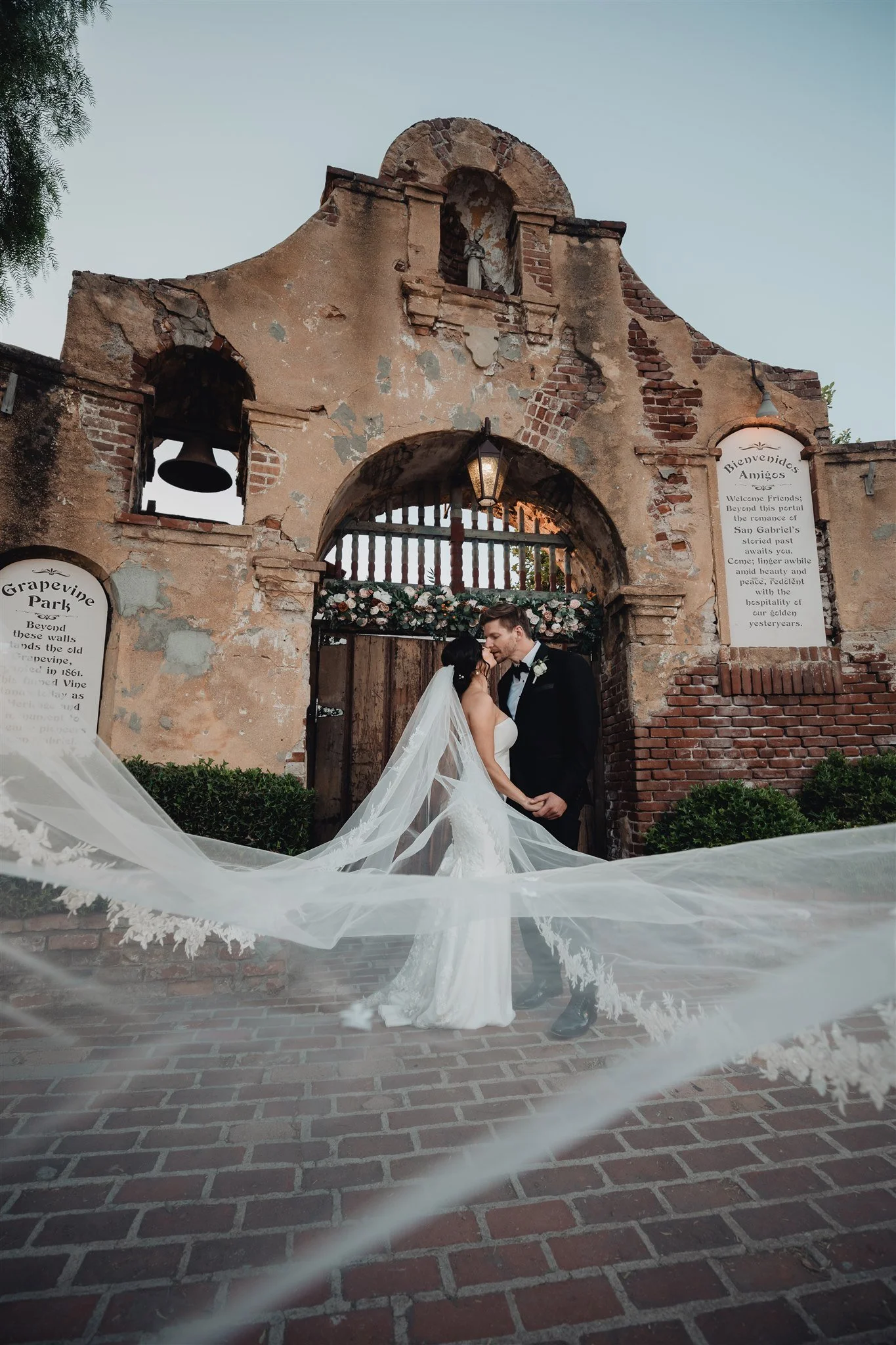 Veil blowing across the brick path at the old arched wall with iron gates at Grapevine Arbor