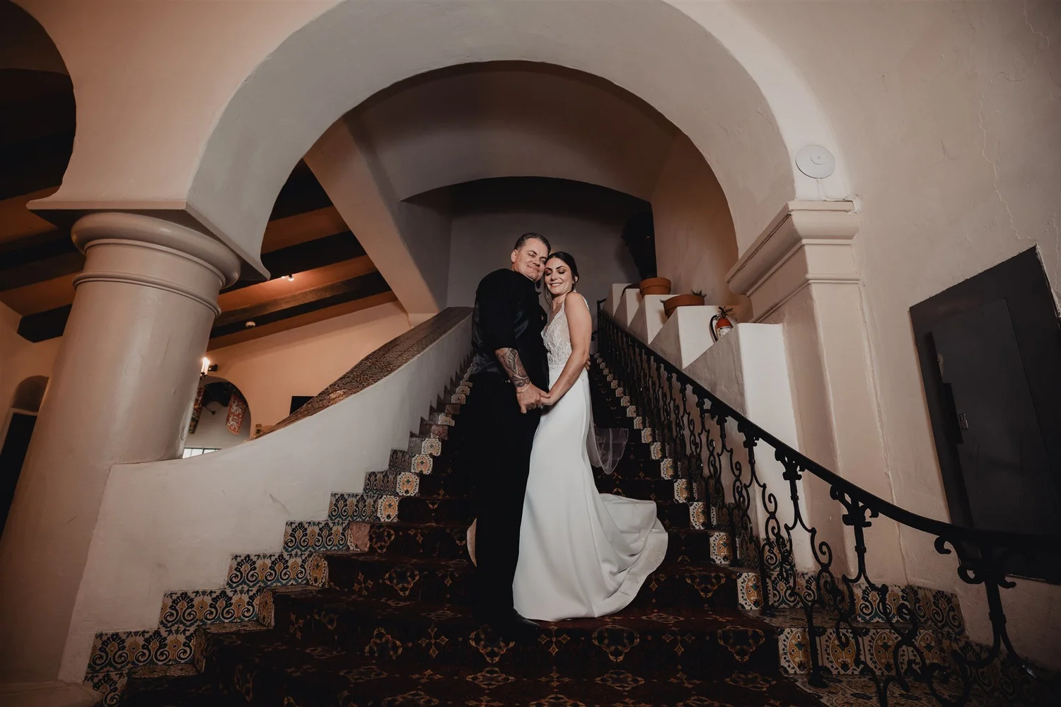 Bride and groom on the tiled staircase beneath the sandstone arch of the Santa Barbara County Courthouse after their ceremony