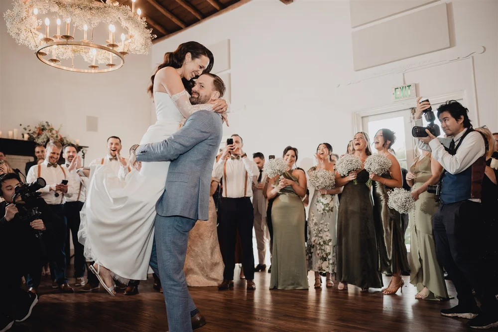 Couple celebrating with guests in the La Venta Inn ballroom under the chandelier