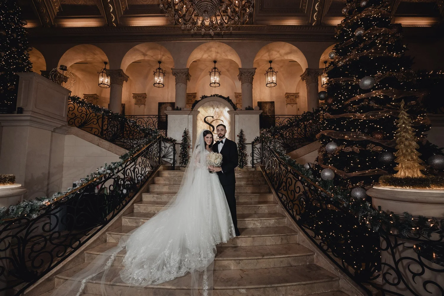 Bride descending the curved staircase beneath arches and lanterns at The Stirling Club