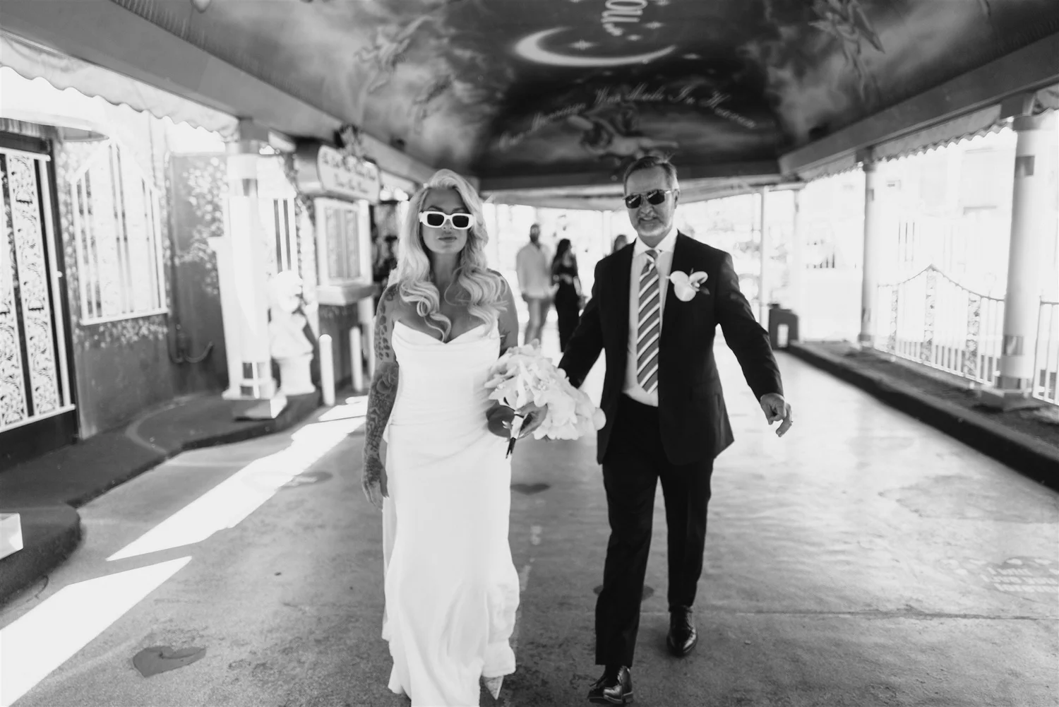Black and white film portrait of couple walking outside the chapel