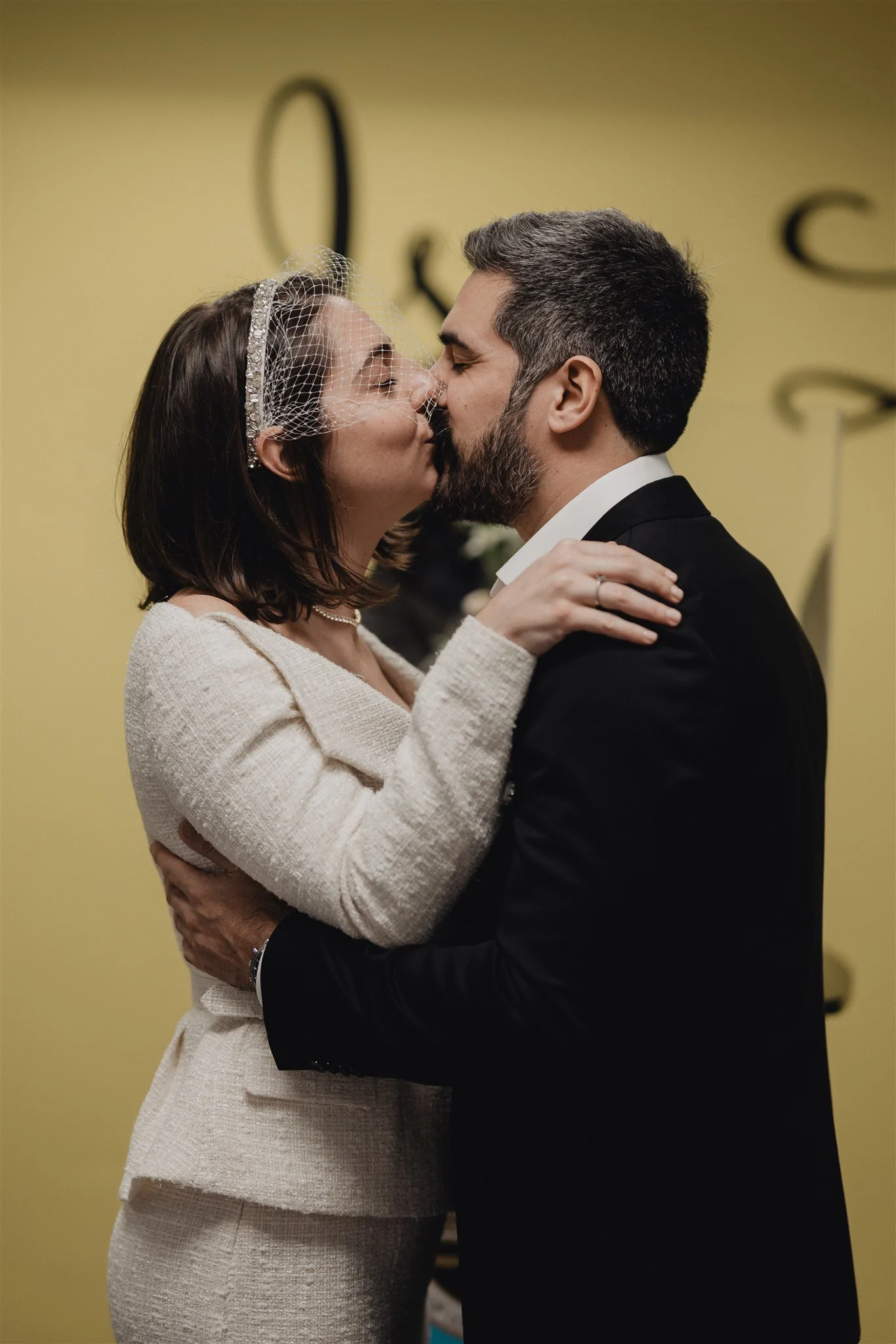 Couple kissing in a courthouse ceremony room, the bride in a cream suit