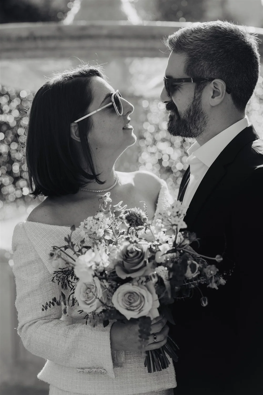 A couple standing forehead to forehead, bouquet in hand, just after their ceremony