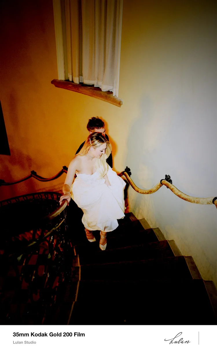 35mm Kodak Gold 200 film — bride descending a grand staircase in warm amber light