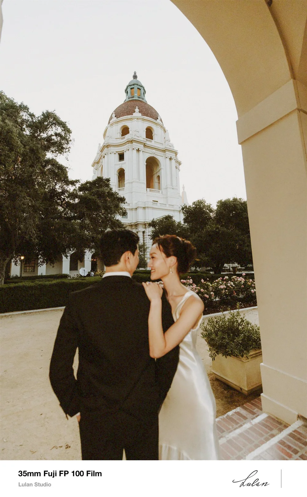Film photo of a couple embracing beneath a stone arch