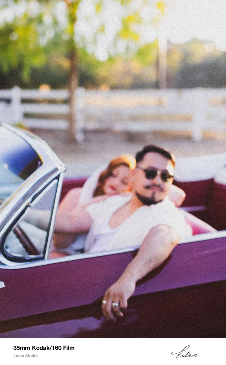 35mm Kodak 160 film — bride and groom in sunglasses riding in a vintage convertible