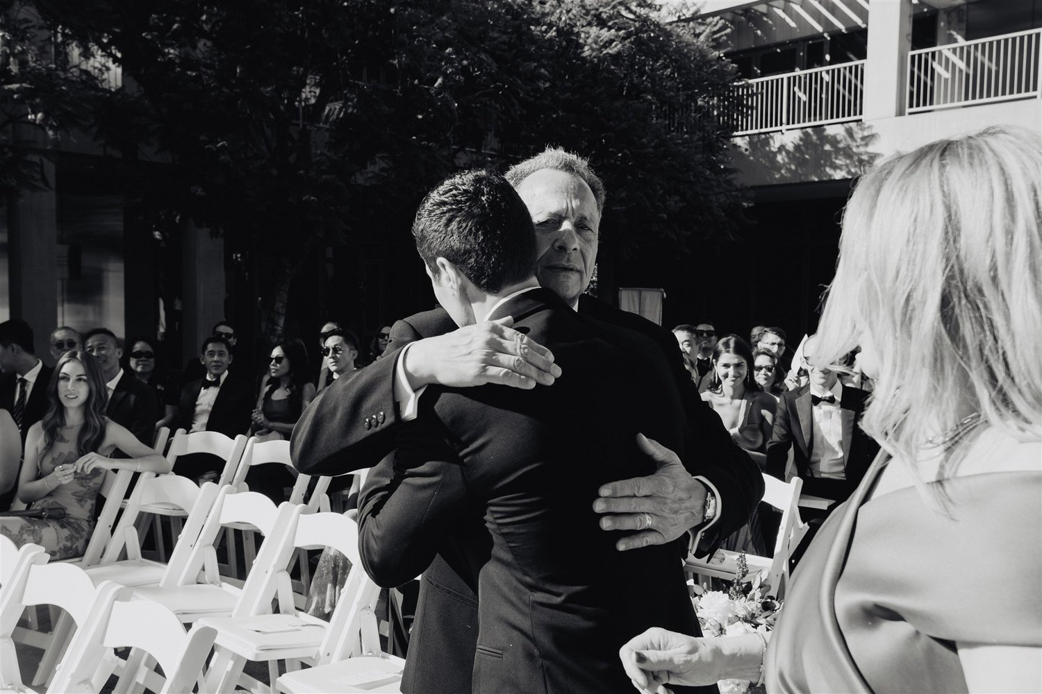 A groom walking down the aisle between both of his parents at a Los Angeles Jewish wedding
