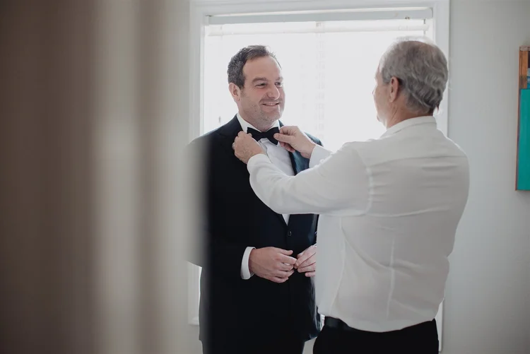 The father of the groom straightening his son's bow tie before the ceremony.