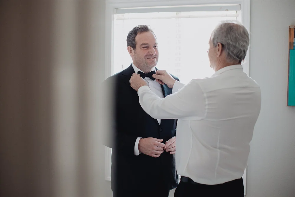 The father of the groom straightening his son’s bow tie before the ceremony