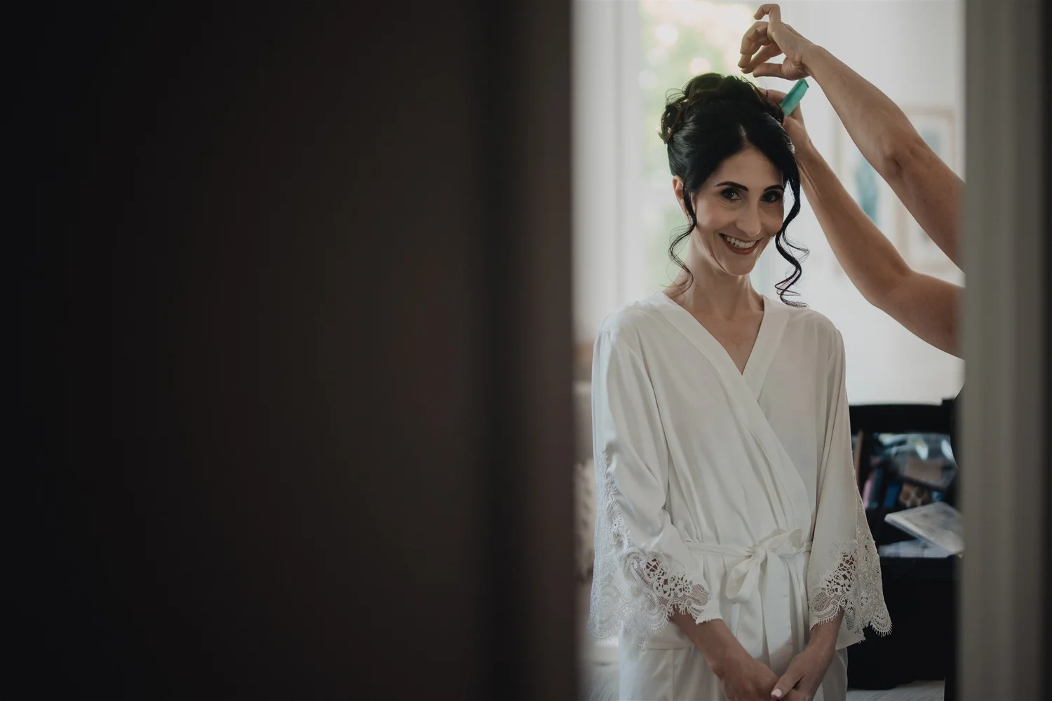 A stylist adds a final pin to a bride's hair before a ceremony