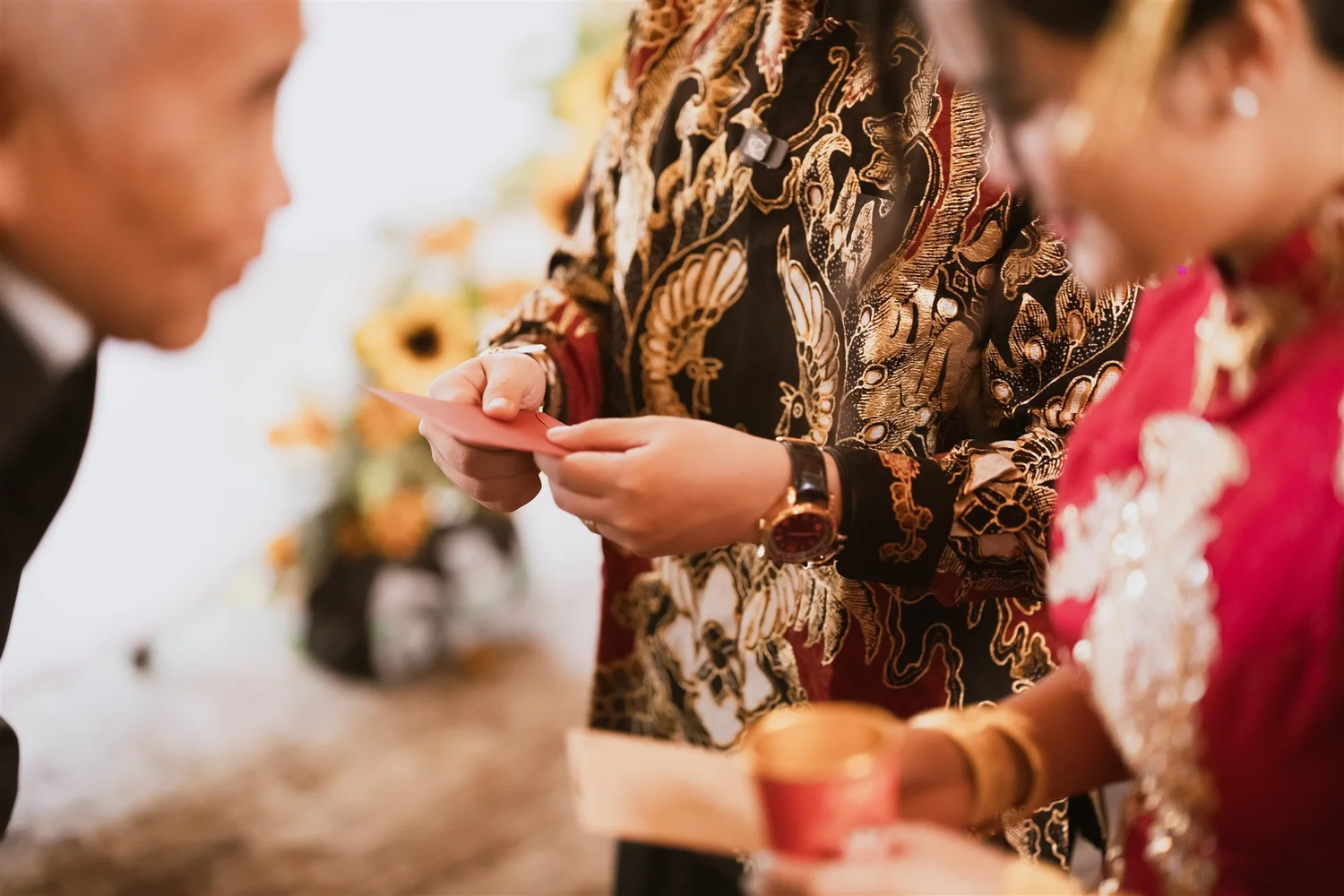 Hands passing a red tea cup between generations at a Chinese wedding tea ceremony