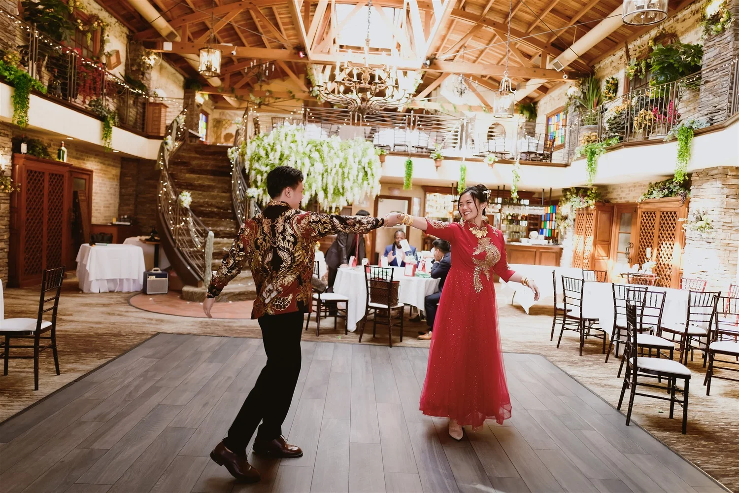 A mother dancing with the bride in a red qipao at a multicultural wedding reception