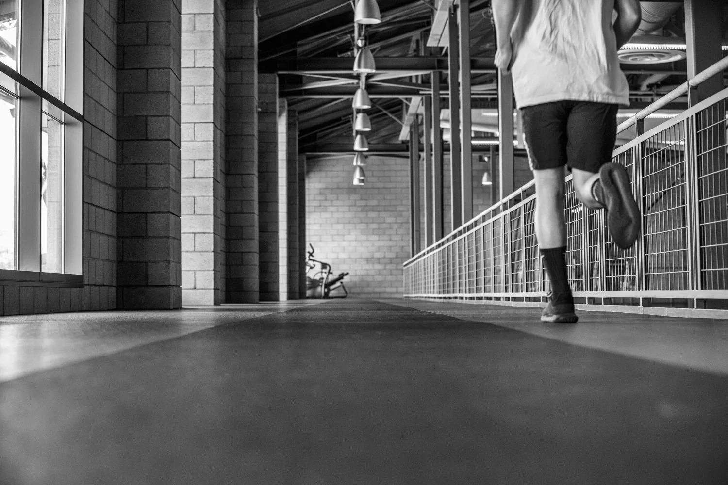 Black and white frame of a person running on a treadmill in a modern gym