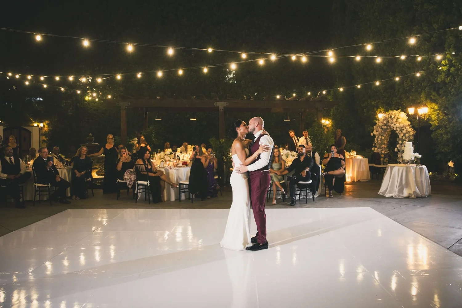 First dance under string lights on the white dance floor at Franciscan Gardens