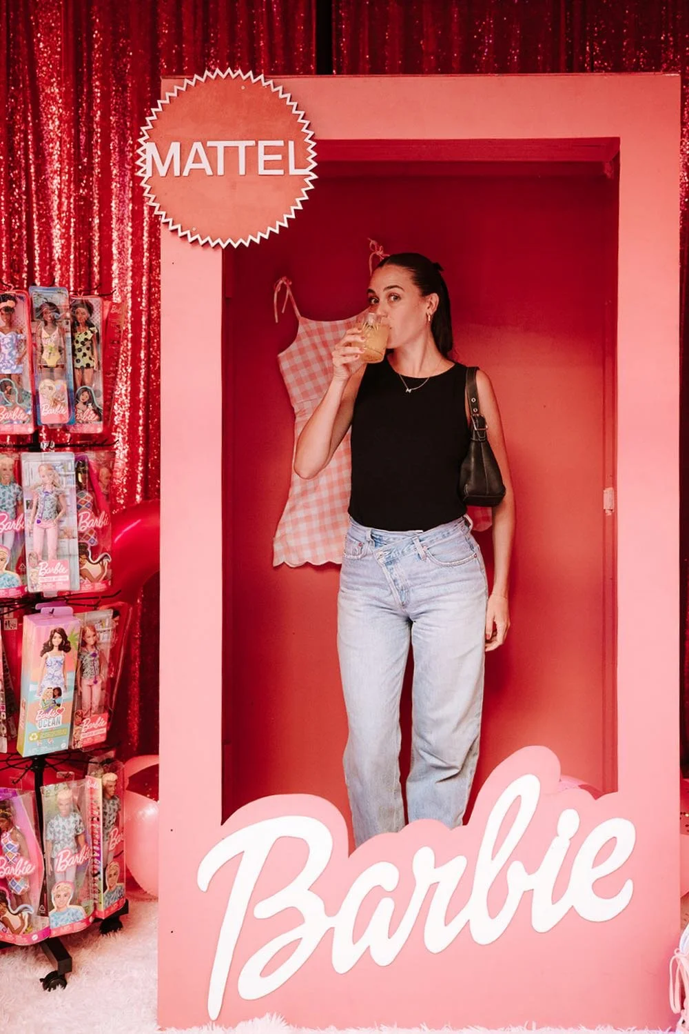 Guest inside a pink Barbie-themed photo booth with dolls on display