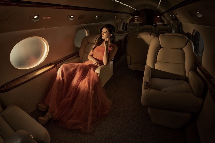 Model in an orange dress photographed in a private jet cabin