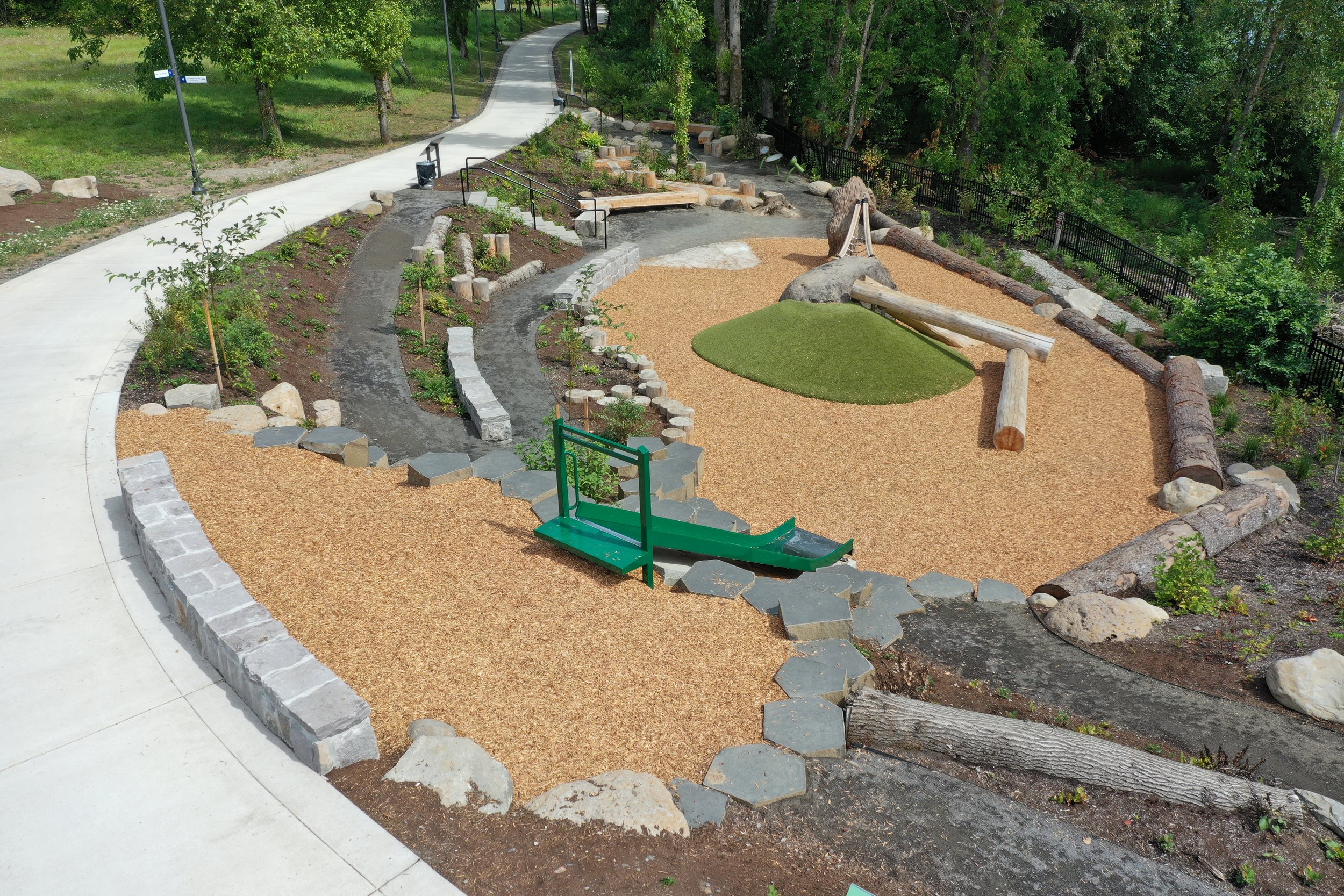 metal slide leading to nature play area on sunny day