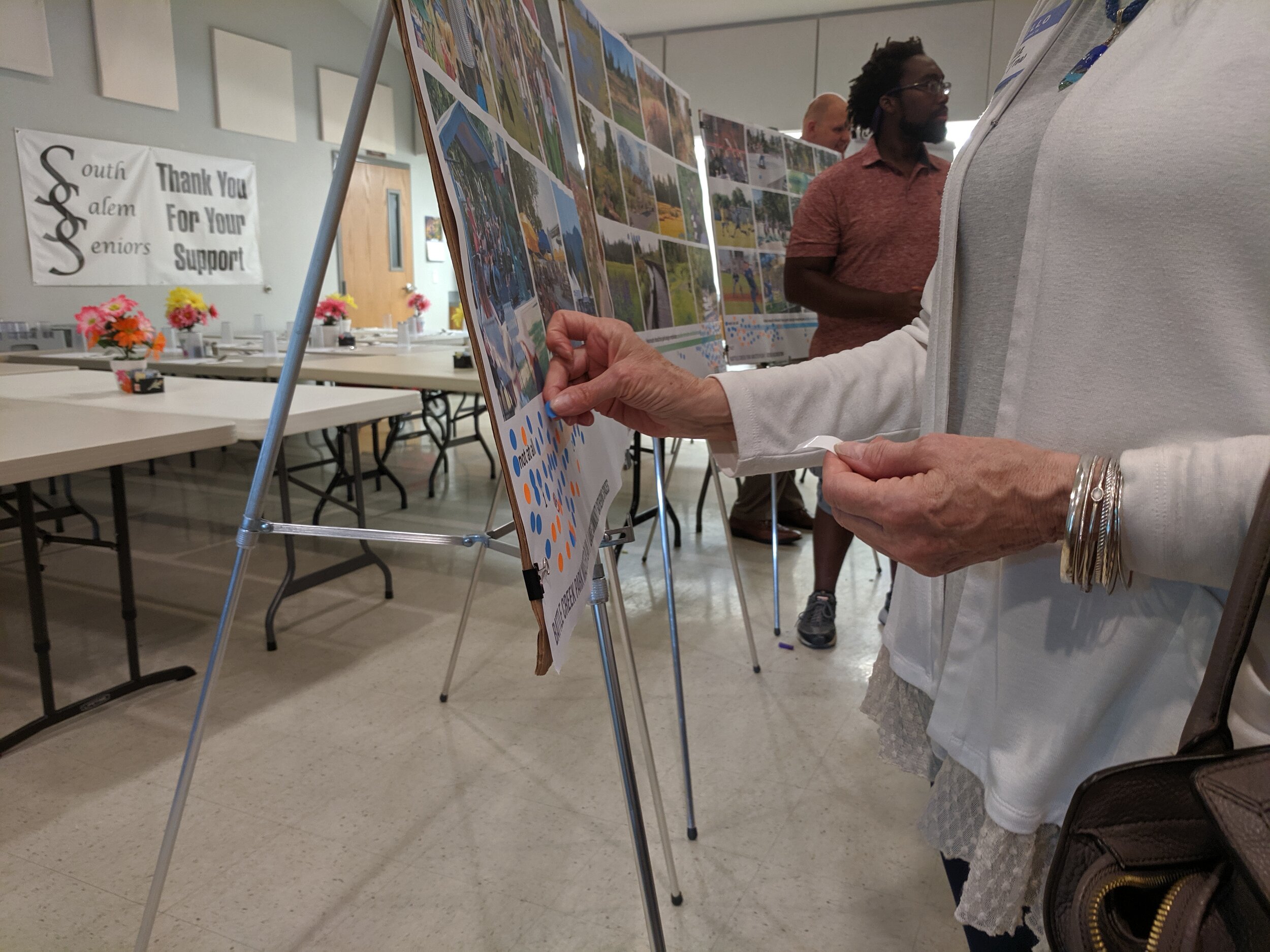 person places dot on poster during a public meeting at salem senior center