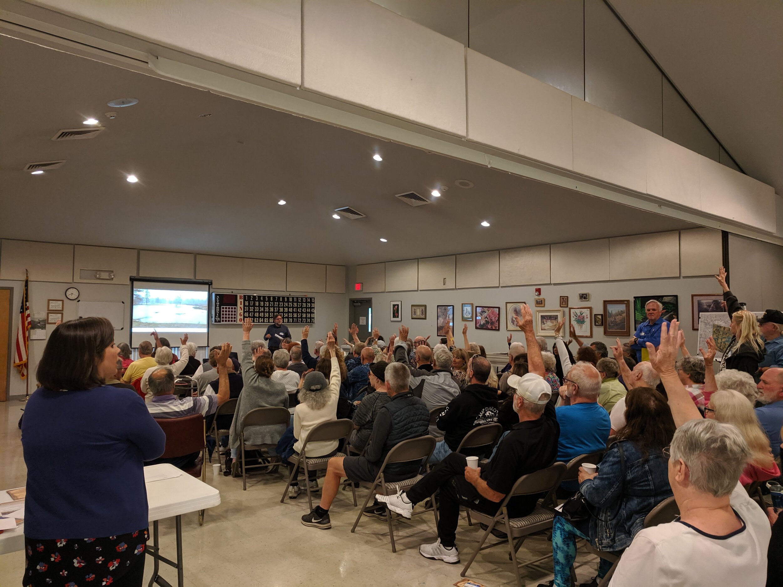 group raises their hands at the salem senior center in a public engagement meeting