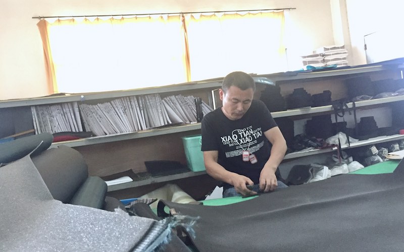 A worker is cutting the fabric of backpacks.