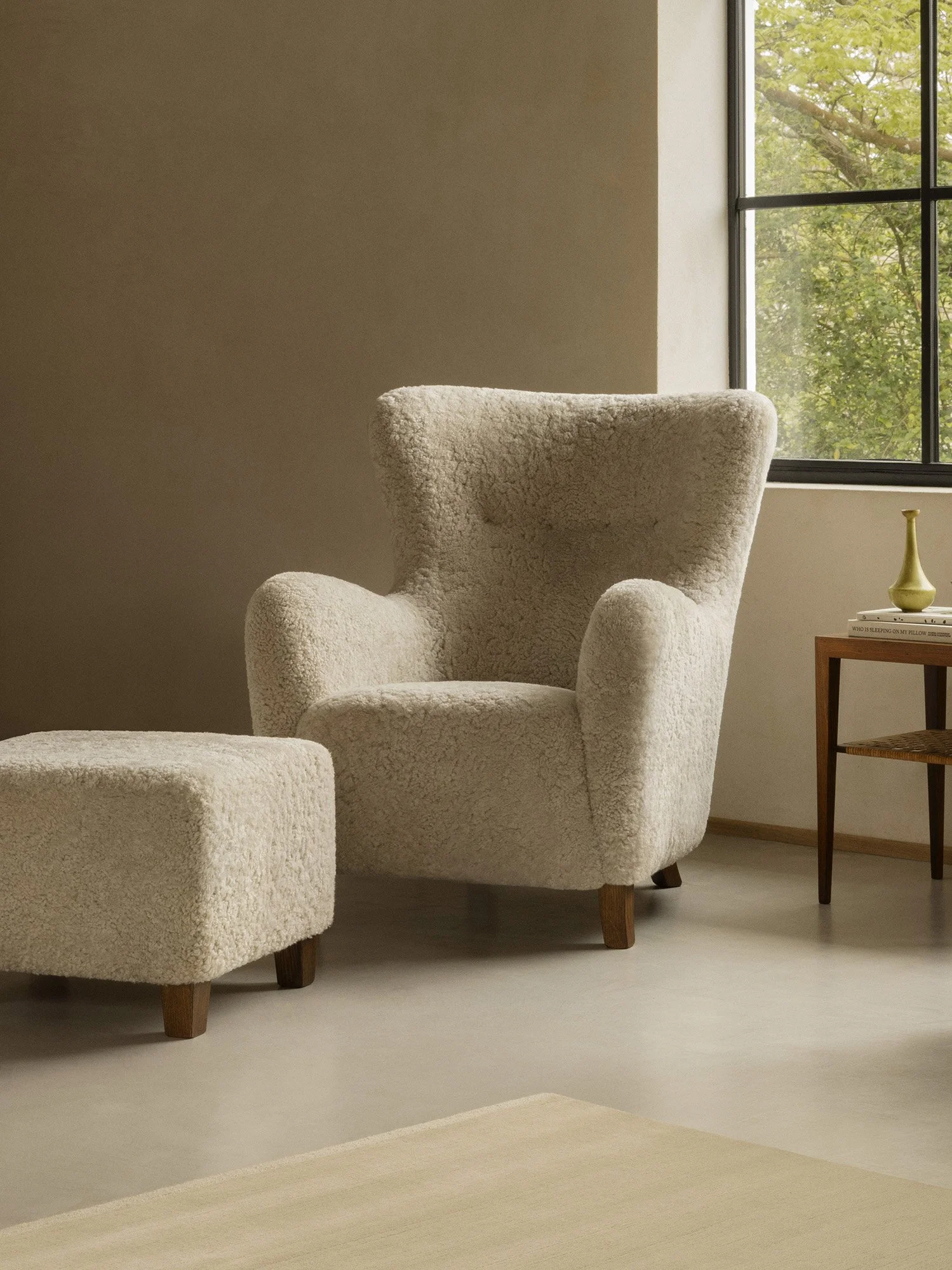 Dagmar's Karu ottoman with curved design in sheepskin upholstery on solid beech wood frame, the matching footstool for the Karu chair collection
