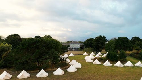 White tipi tents in grounds of a wedding venue for a large festival wedding in the UK