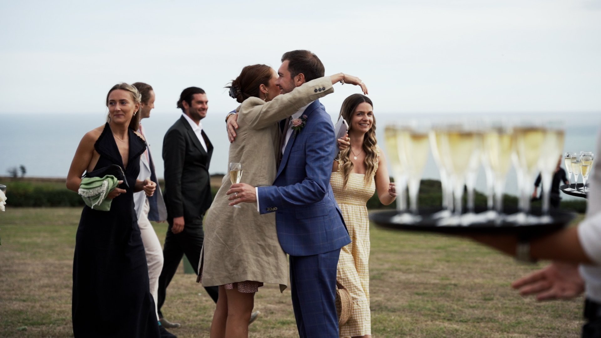 Guests embracing at outdoor wedding in field