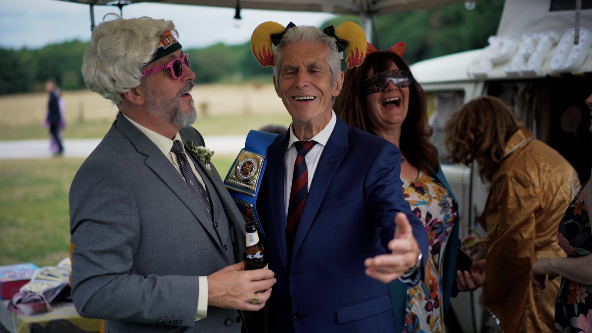 Guests at a wrestling themed wedding wearing fun props on their heads while laughing and drinking bottled beer