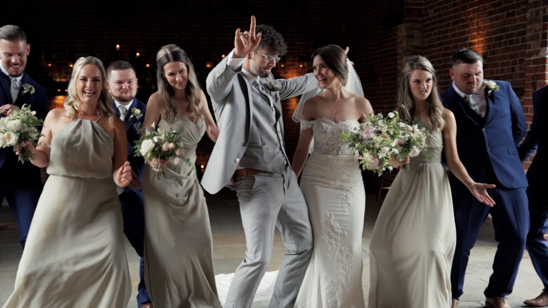 Bride and groom dancing on their wedding day with three bridesmaids and two groomsmen all dressed in formal wedding party attire