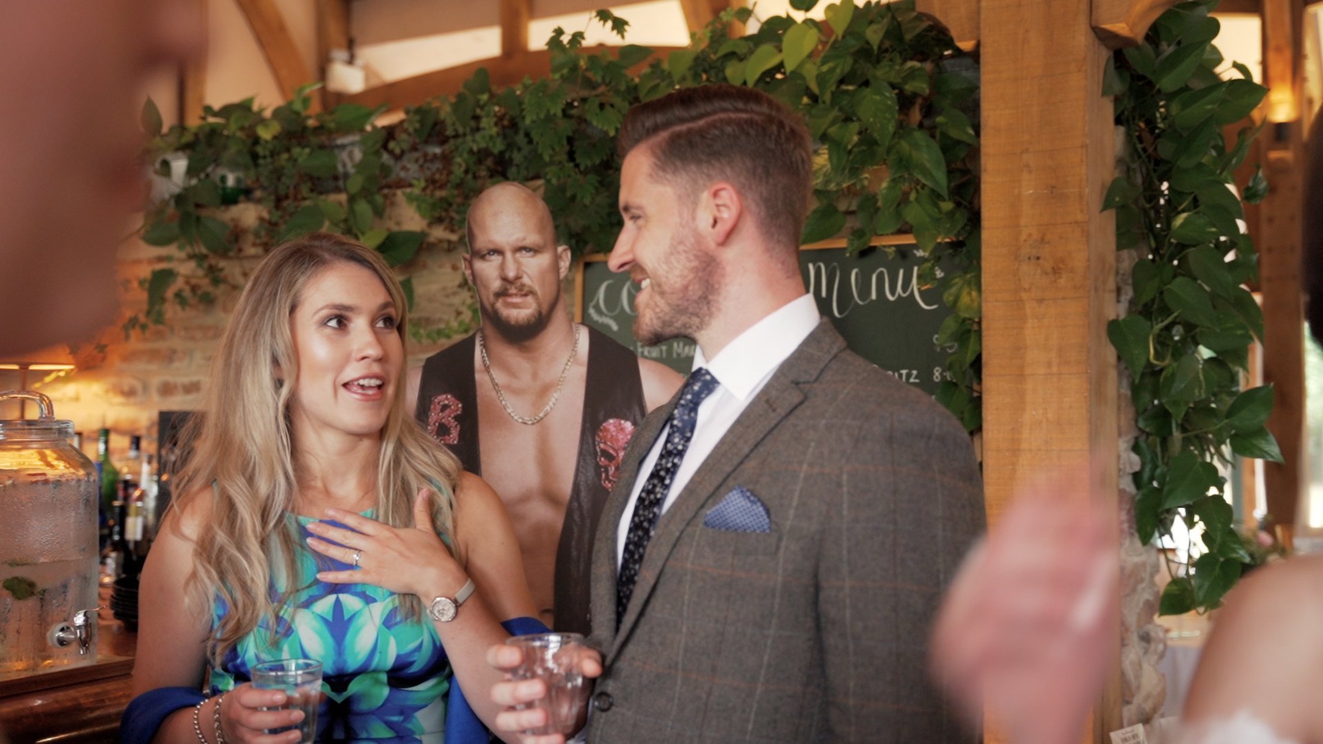 Wedding guests wearing formal attire chatting and standing in front of lifesized wrestling cut out