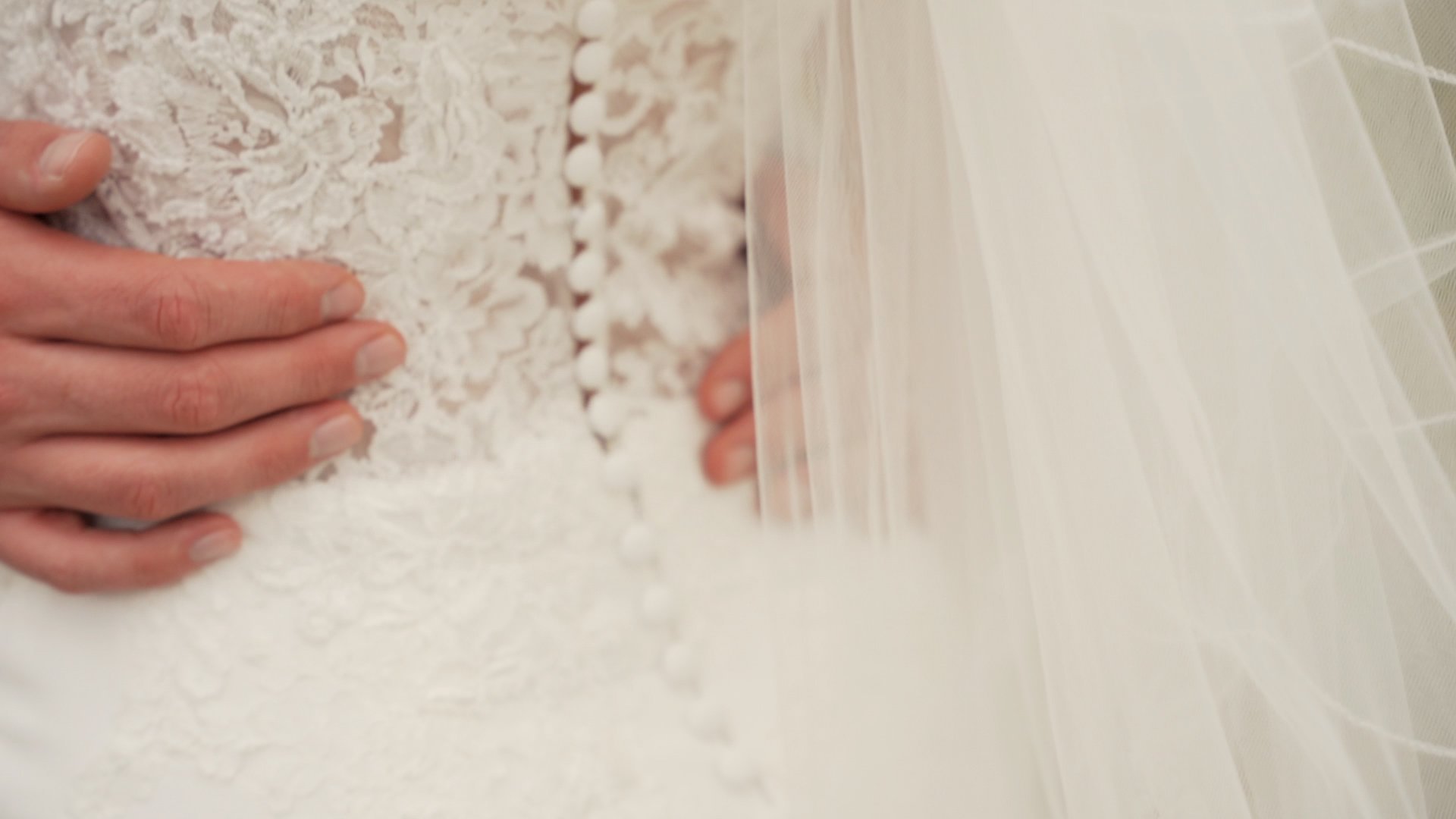 Beautiful up close photography of an intricate lace pattern and buttons on back of white wedding dress