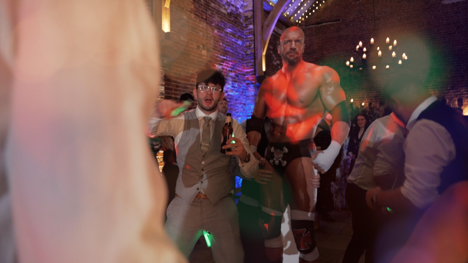A newly-married groom dancing at his WWE themed wedding reception in front of a life-sized cut out of a wrestler