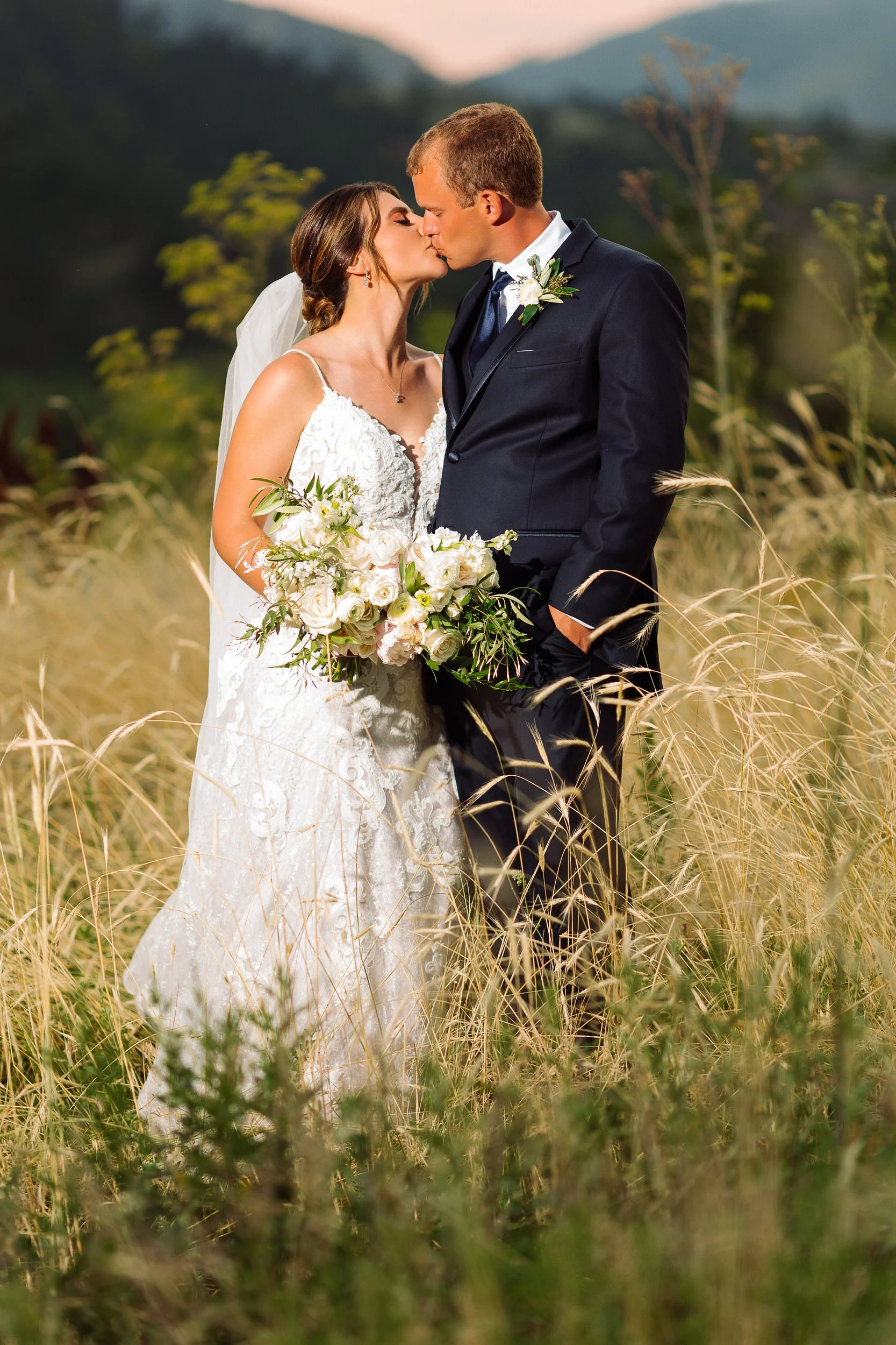 A formally dressed couple kisses in a field during a Greenbriar Inn wedding in Boulder, Colorado