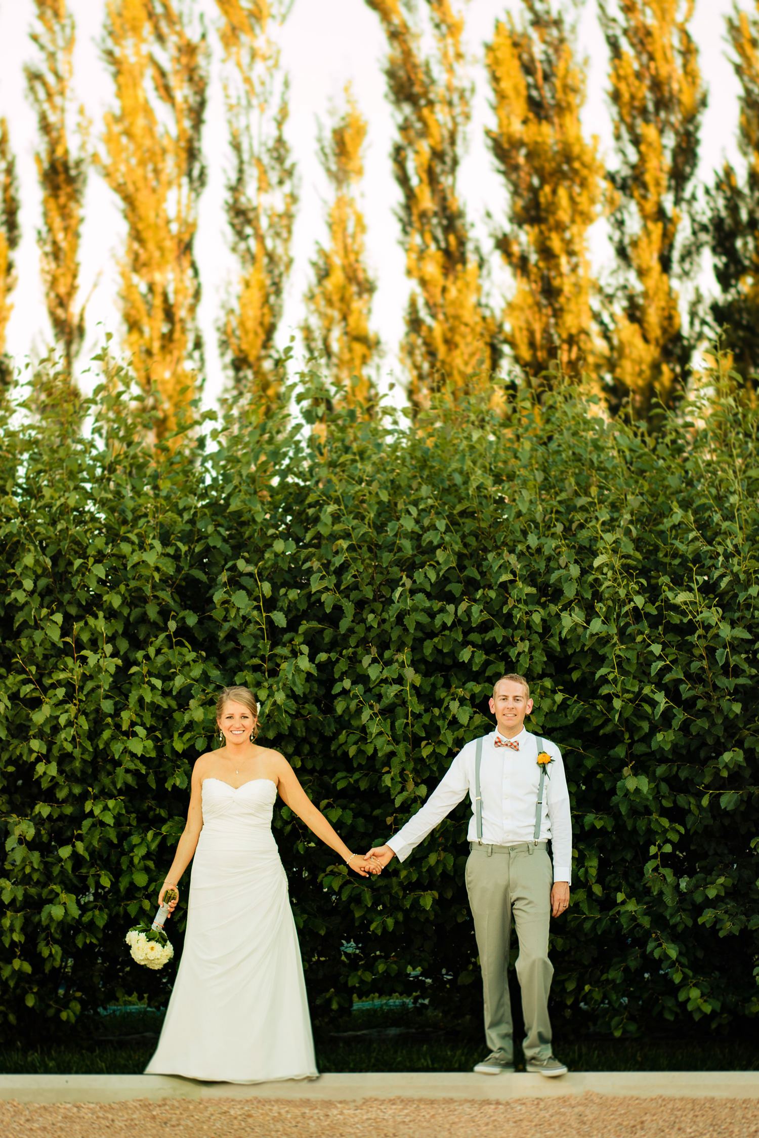 bride and groom hold hands in a summer breeze during a preserve at bingham hill wedding near Fort Collins, Colorado.