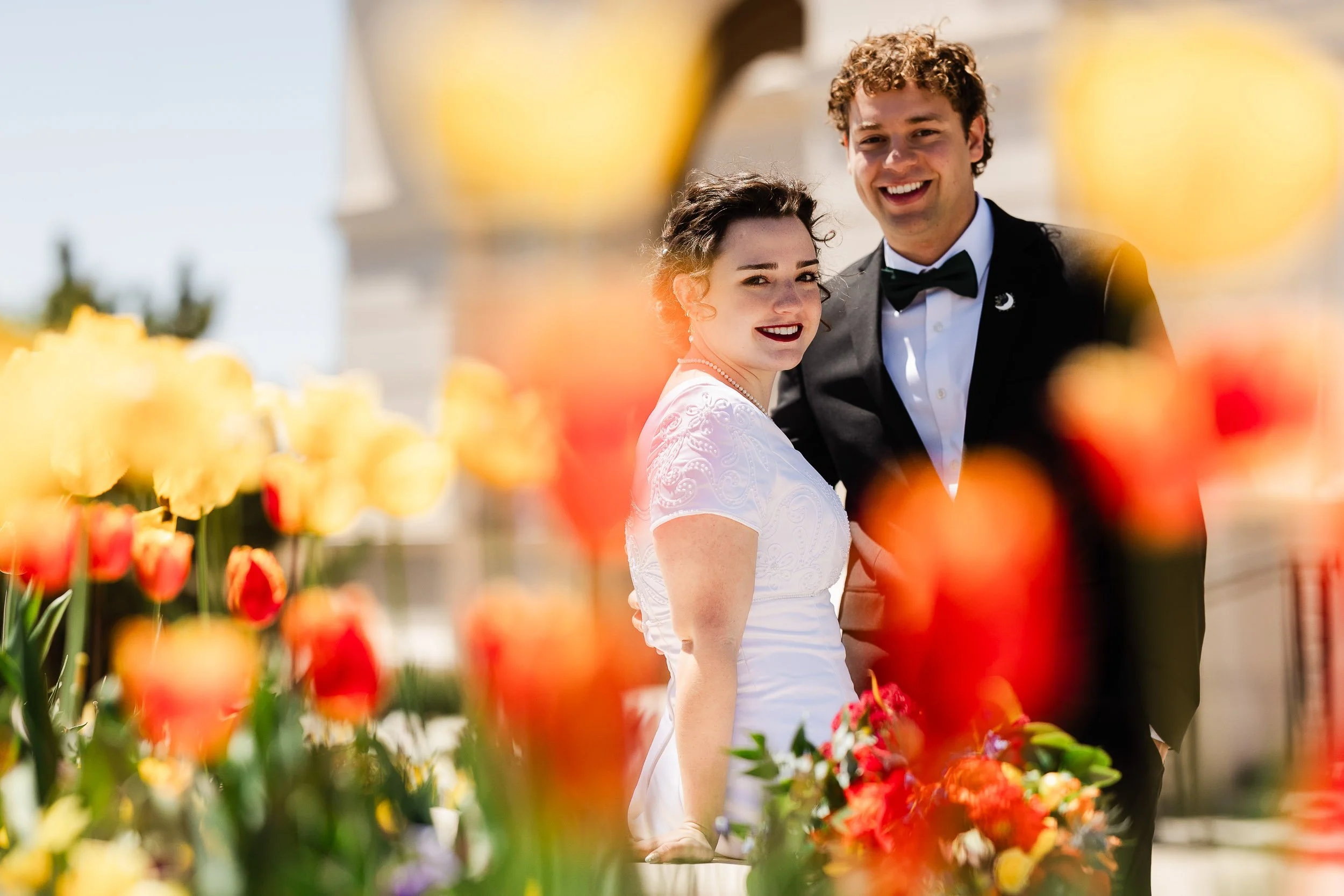 Bride and groom relaxe among the Summer flowers on the grounds of the LDS Temple after a wedding ceremony in Fort Collins, Colorado