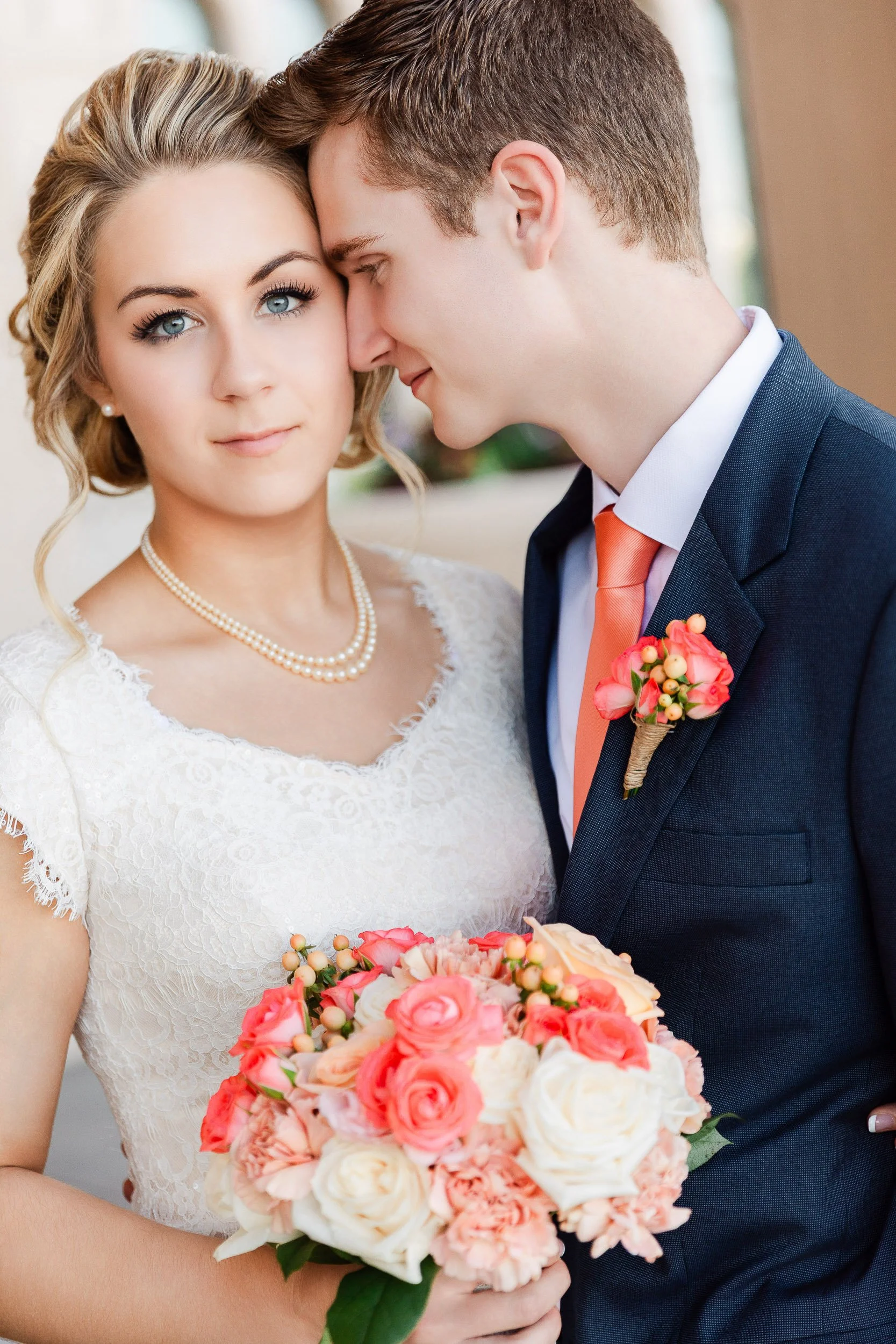 Bride gazes into camera lens while groom nuzzles into her ear after a wedding at the LDS Temple in Fort Collins, Colorado