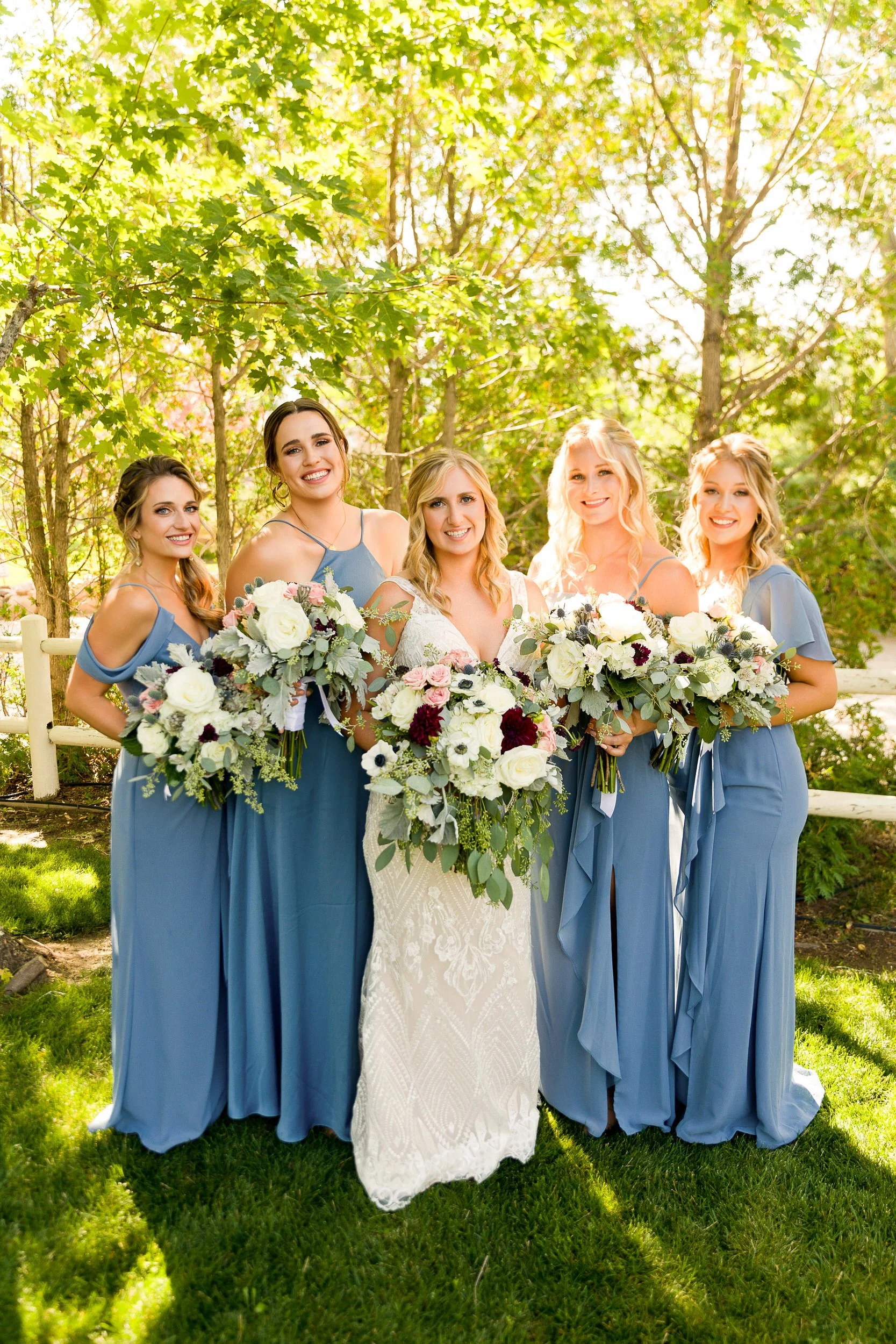 Bride and her bridesmaids dressed in blue pose among the backlit trees before a Greenbriar Inn wedding in Boulder, Colorado