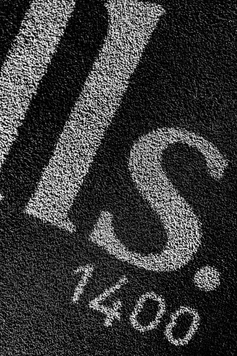Close-up of textured black and white surface showing partial letters and numbers "1400," conveying an abstract, industrial feel.