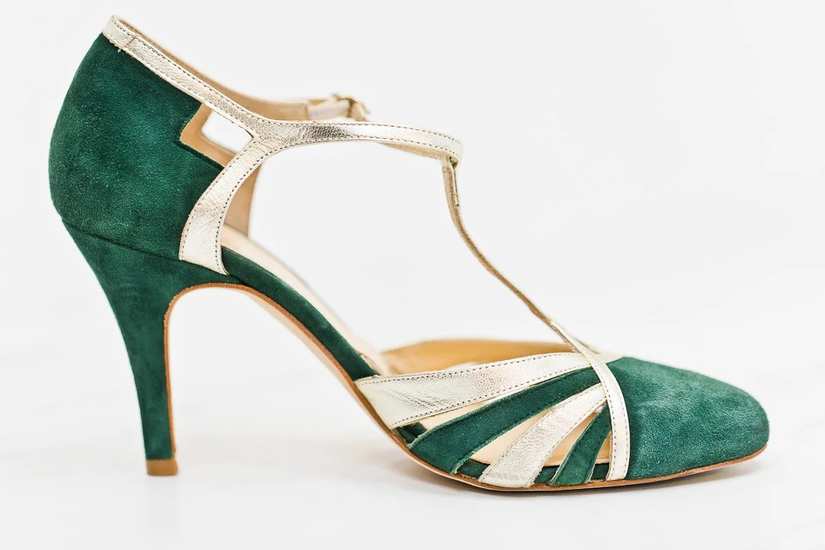 Elegant green and cream suede high heel shoe with a T-strap design on a white background. The shoe conveys a sophisticated and vintage style.