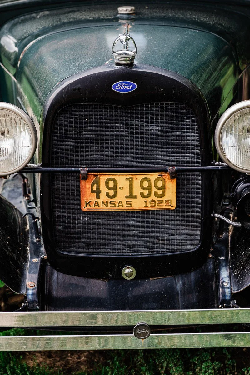 Close-up of the front of a vintage Ford car with a Kansas 1929 license plate, number 49-199. The car is in black with distinctive round headlights.