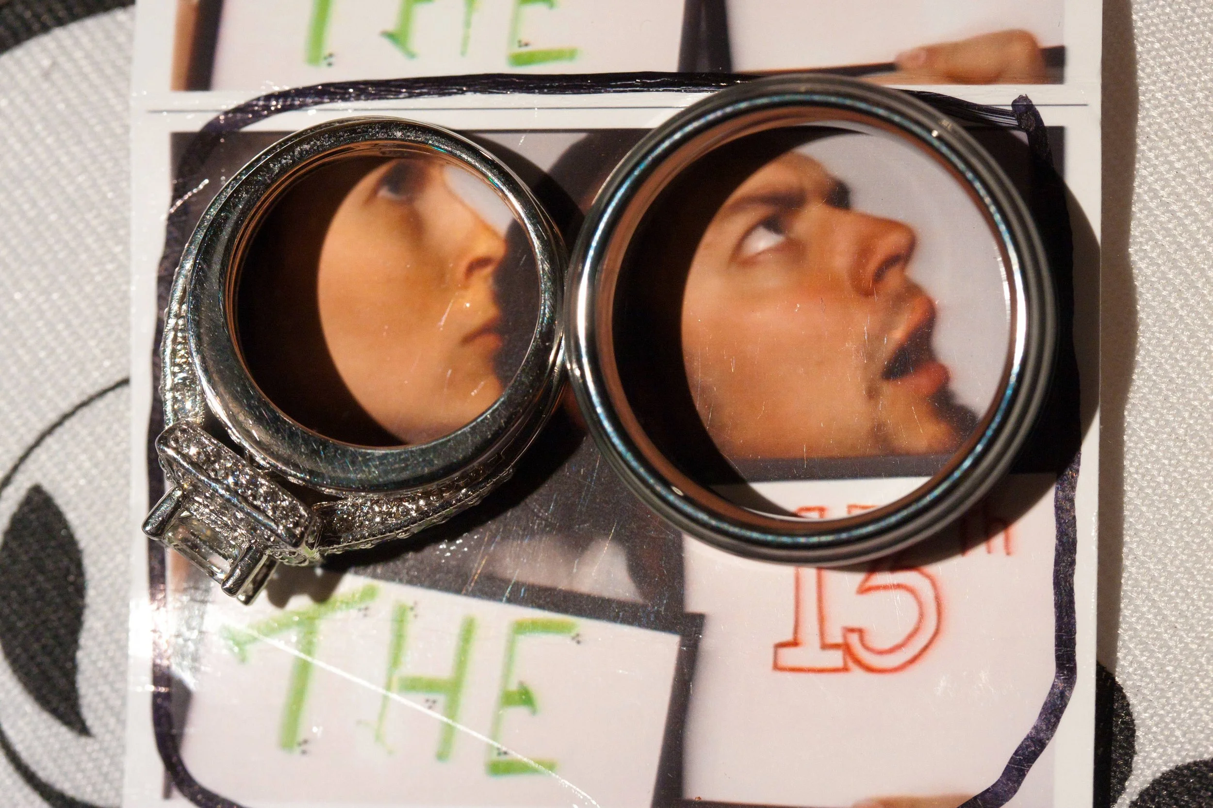 Close-up of two rings placed over a photo strip, each framing a person's face looking upward. Emotion: Curiosity. Words "THE" and "13th" are visible.