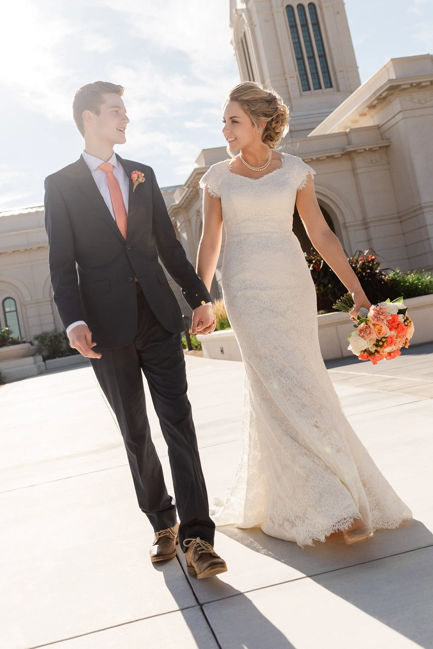 A bride and groom walk holding hands while discussing their future after a wedding at the LDS Temple in Fort Collins, Colorado