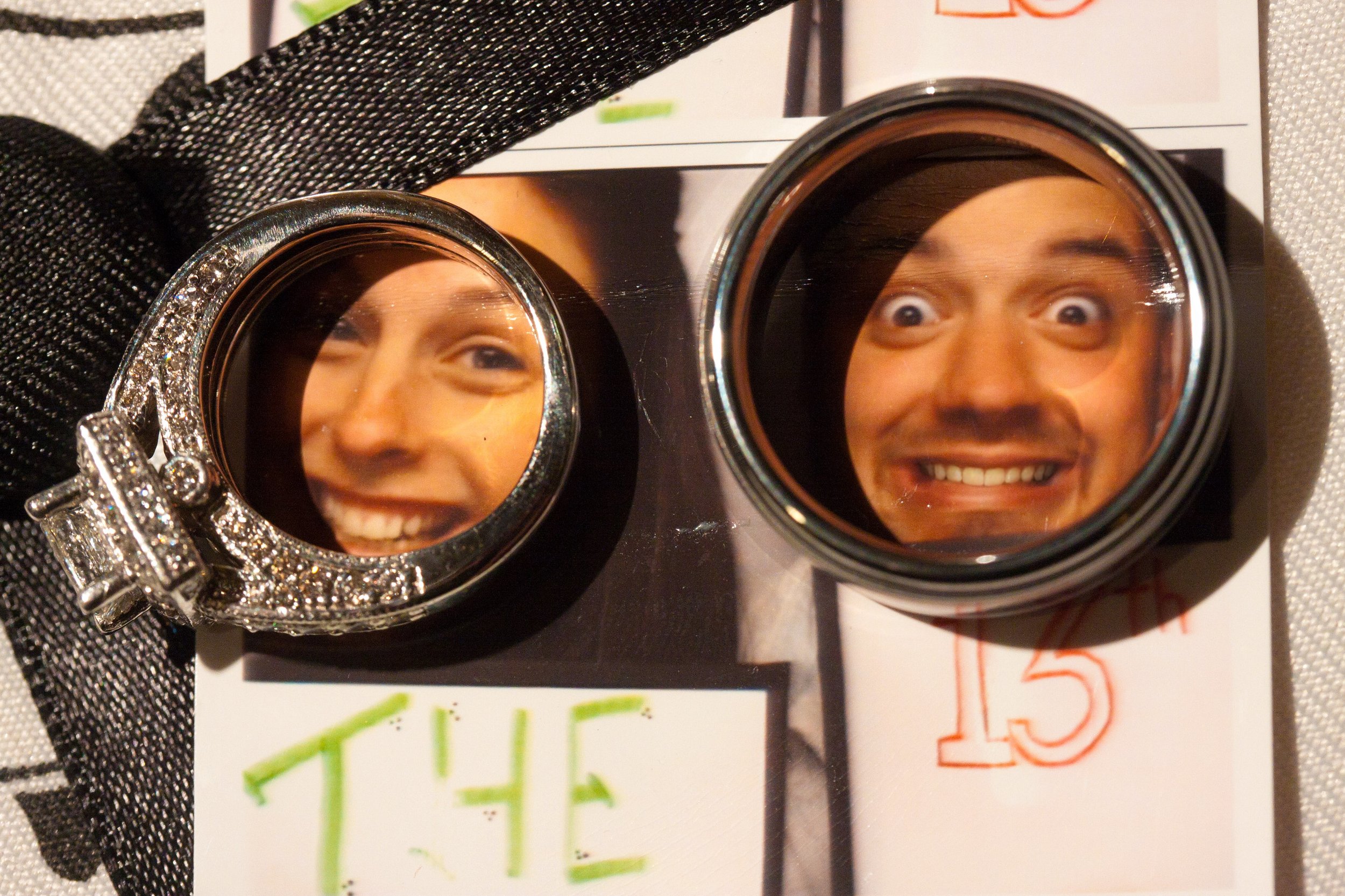 Two rings magnify smiling faces on a photo strip. One ring has diamonds, and both rest on an image with playful, happy expressions.