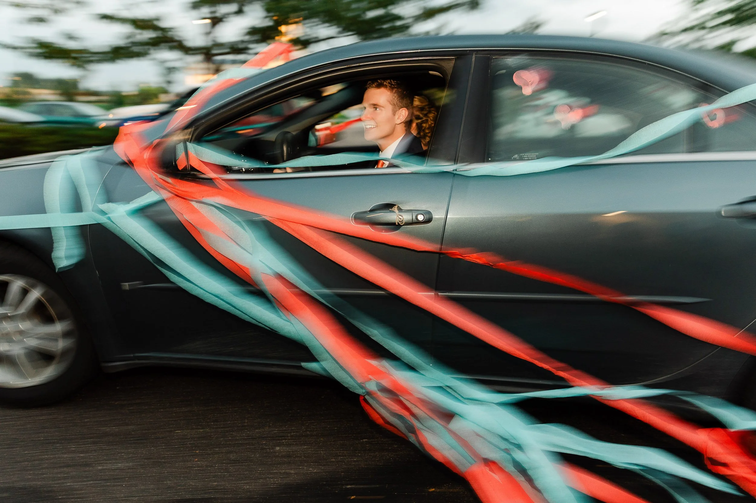 Bride and groom race away in a streamer cover getaway car after a wedding at the LDS Temple in Fort Collins, Colorado.