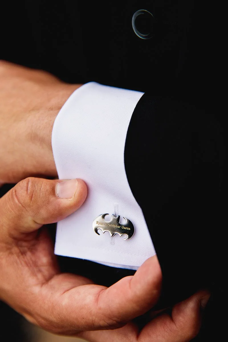 A bride in a white lace gown holds a bouquet while standing with a groom and two attendants. The group smiles warmly in a warmly lit, elegant venue.