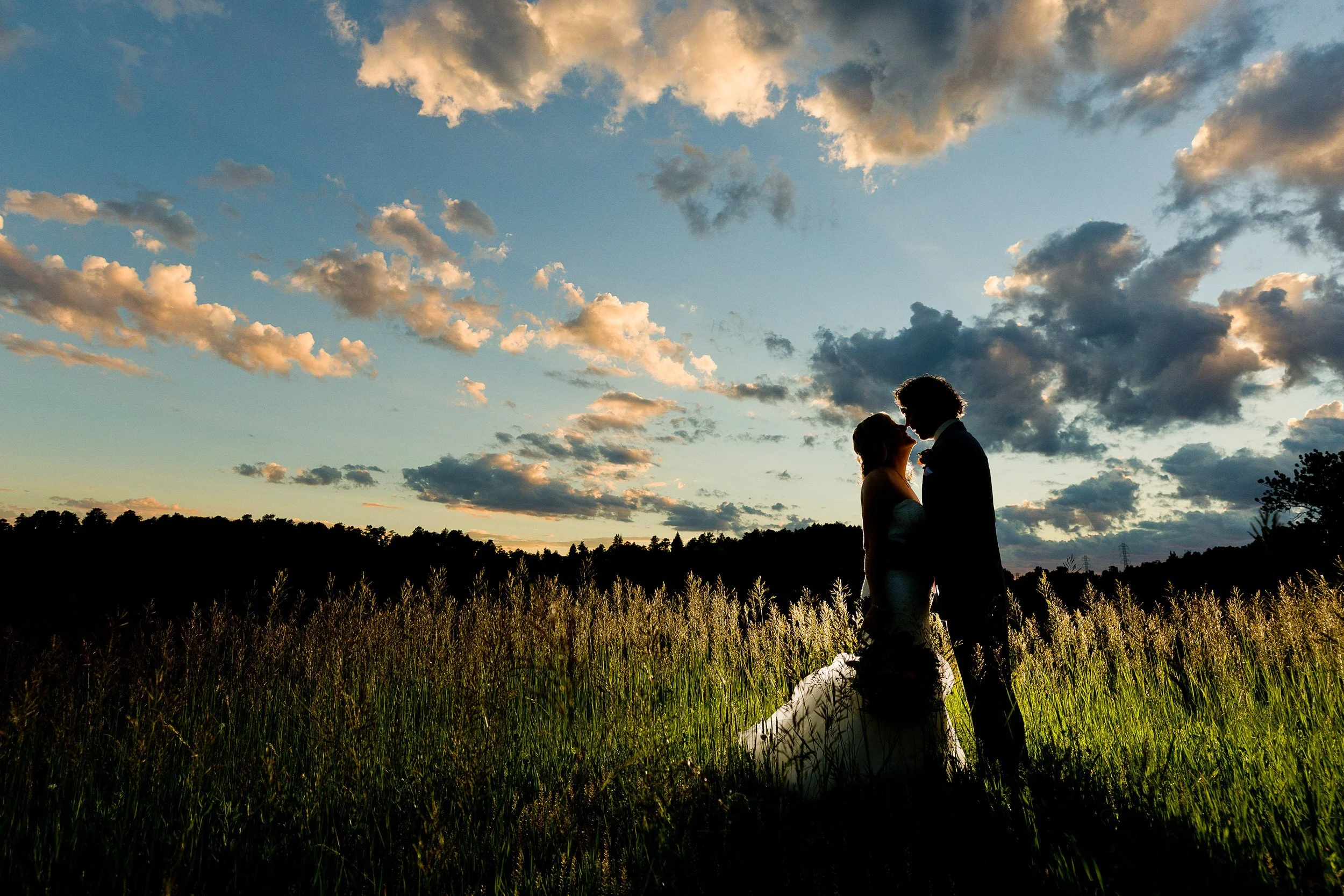 Dramatic Summer sunset sky frames a couple sharing a quiet moment during a Mount Vernon Canyon Club wedding in Golden, Colorado