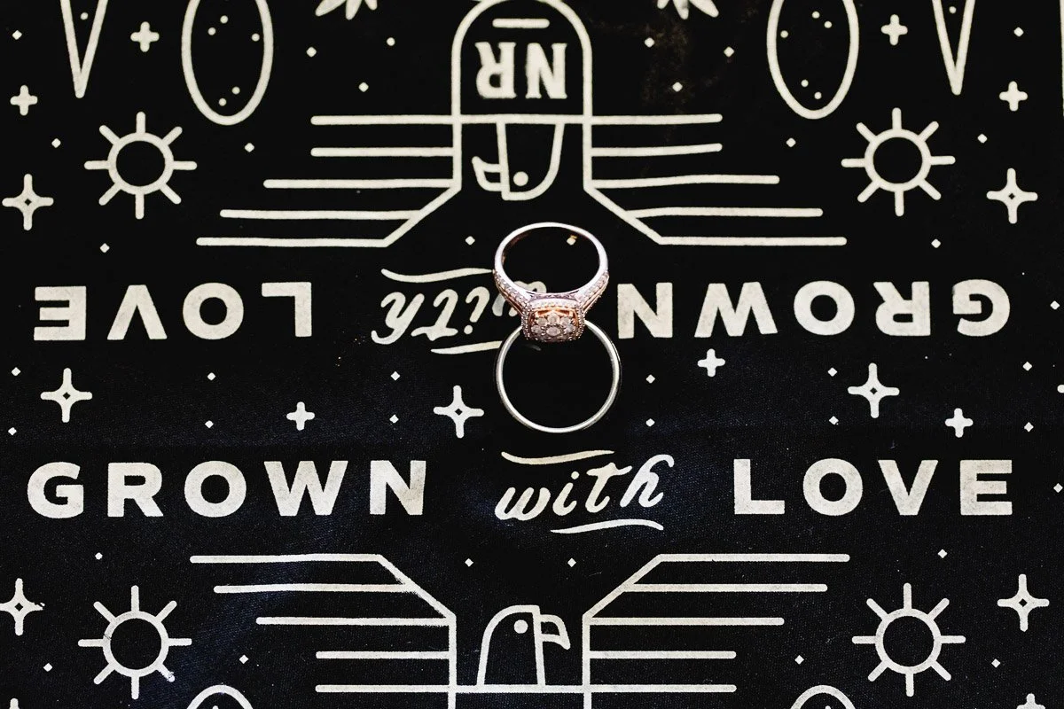 A silver ring with a diamond sits at the center, surrounded by a pattern with suns and stars. The text "Grown with Love" is visible on a black background.