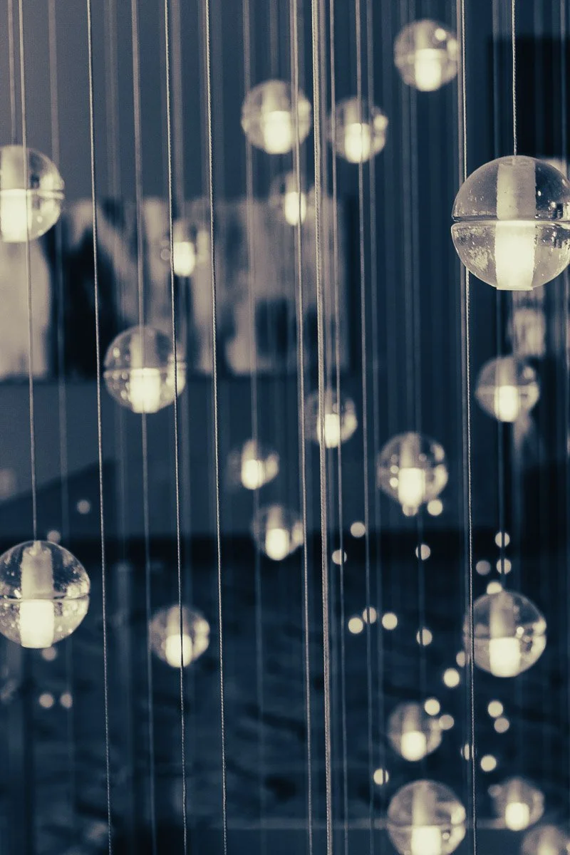 Hanging spheres with soft glowing lights suspended on wires create a serene, ambient atmosphere. The background is blurred, enhancing the focus on the lights.